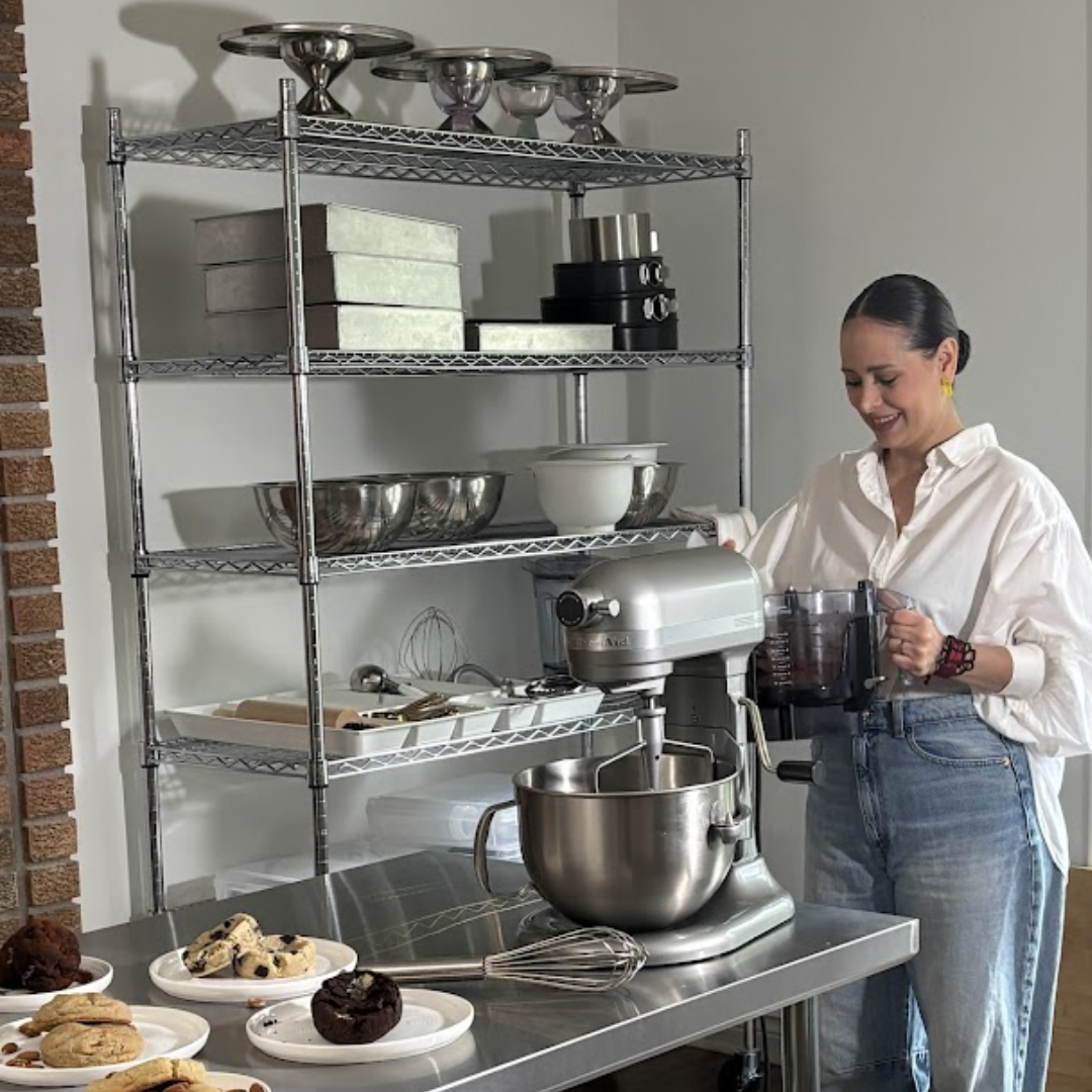 Woman using a stand mixer in a kitchen mixing ingredients and baking healthy cookies.